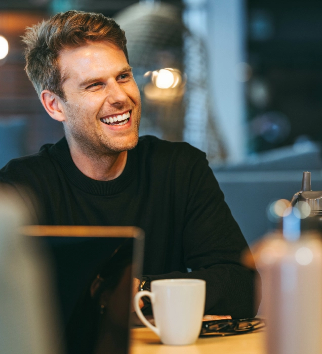 a man smiling having a coffee